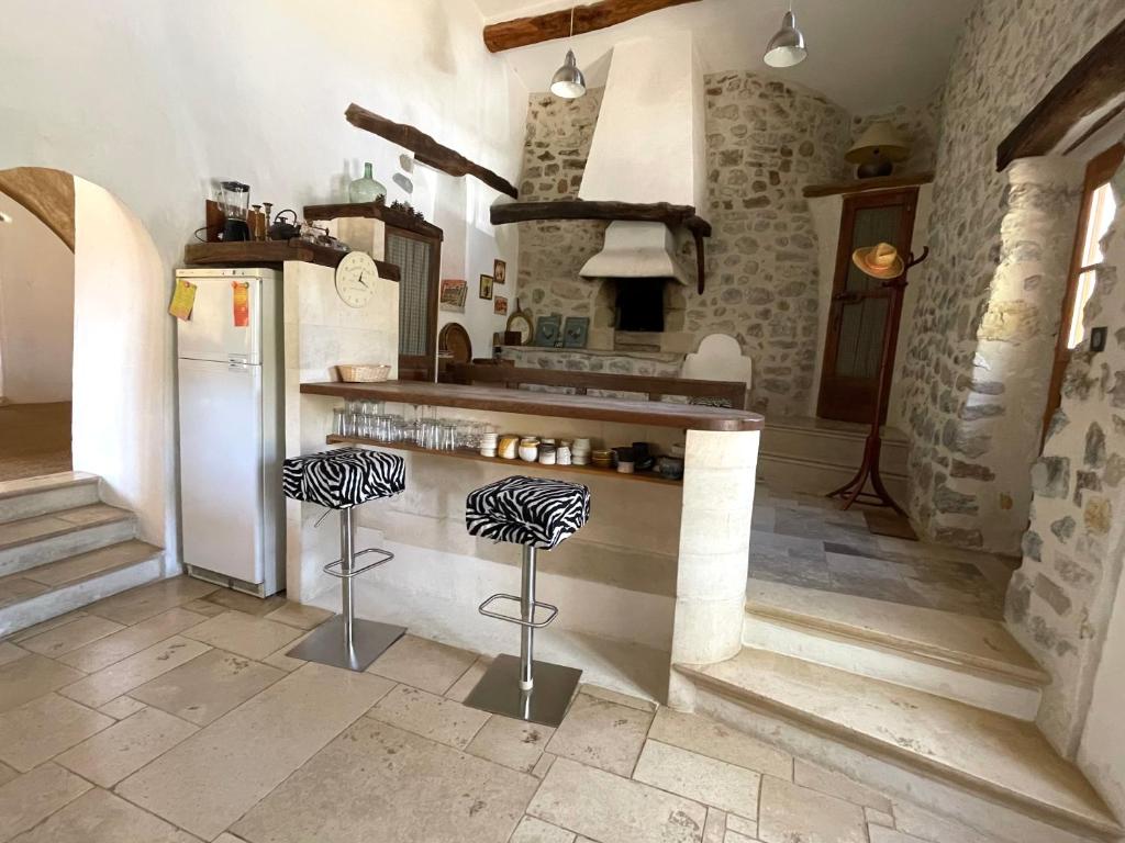 eine Küche mit einem Kühlschrank und einer Theke mit Stühlen in der Unterkunft La Maison de Vergol in Montbrun-les-Bains