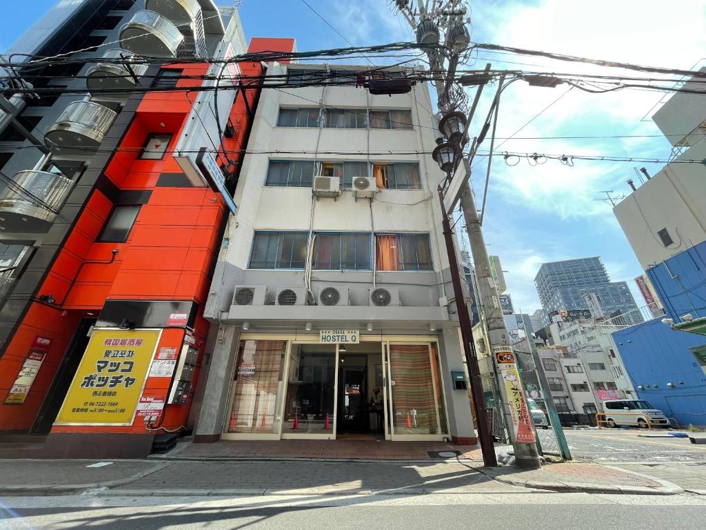 un edificio con una fachada de naranja en una calle de la ciudad en Hostel Q en Osaka