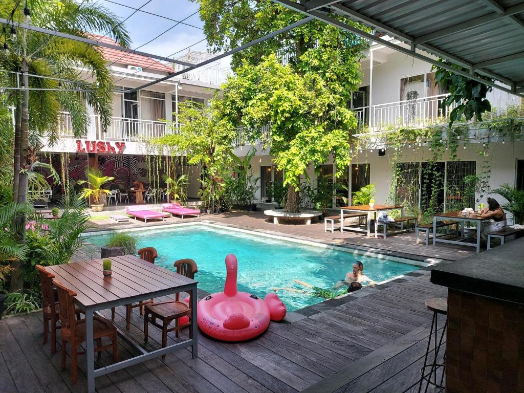 una piscina con tavolo e un bambino in acqua di Lushy Hostel Canggu a Canggu