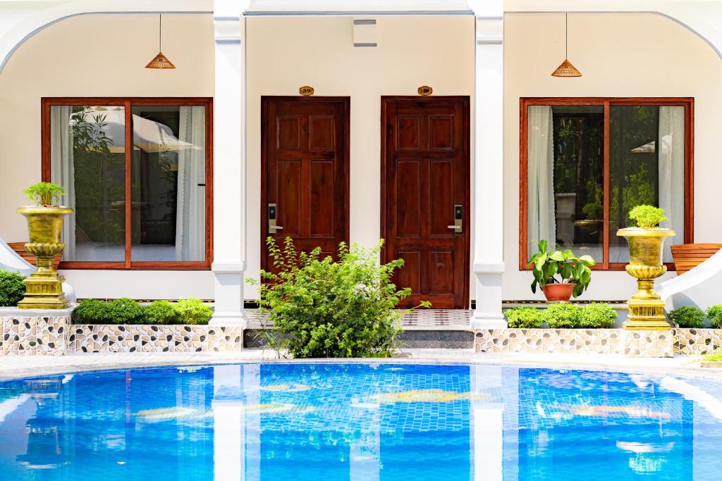 a villa with a swimming pool in front of a house at Kim Xuan Bungalow in Phu Quoc