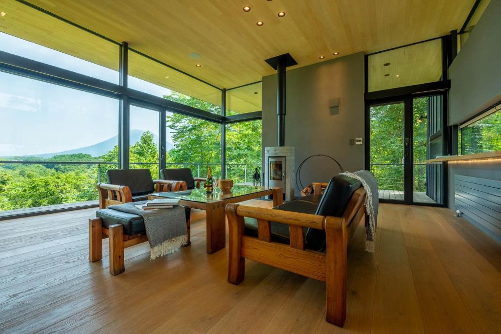 a living room with a table and chairs and windows at Hiyoku 飛翼 in Niseko