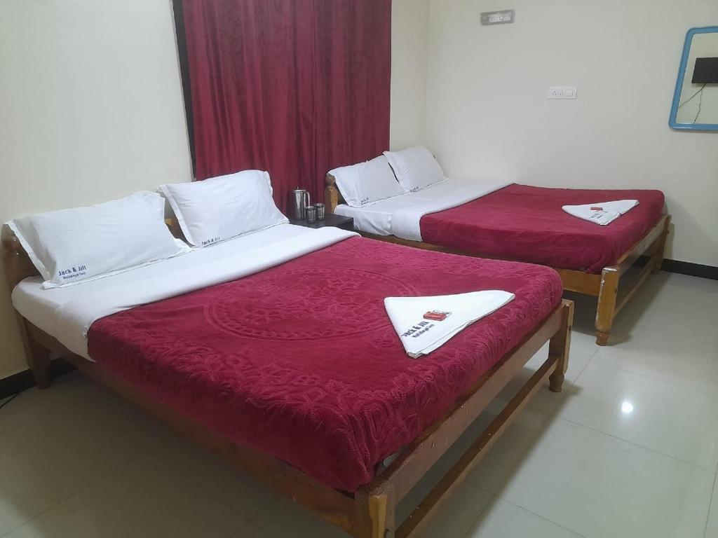two beds in a hotel room with red sheets at jack N jill holidays inn in Ooty