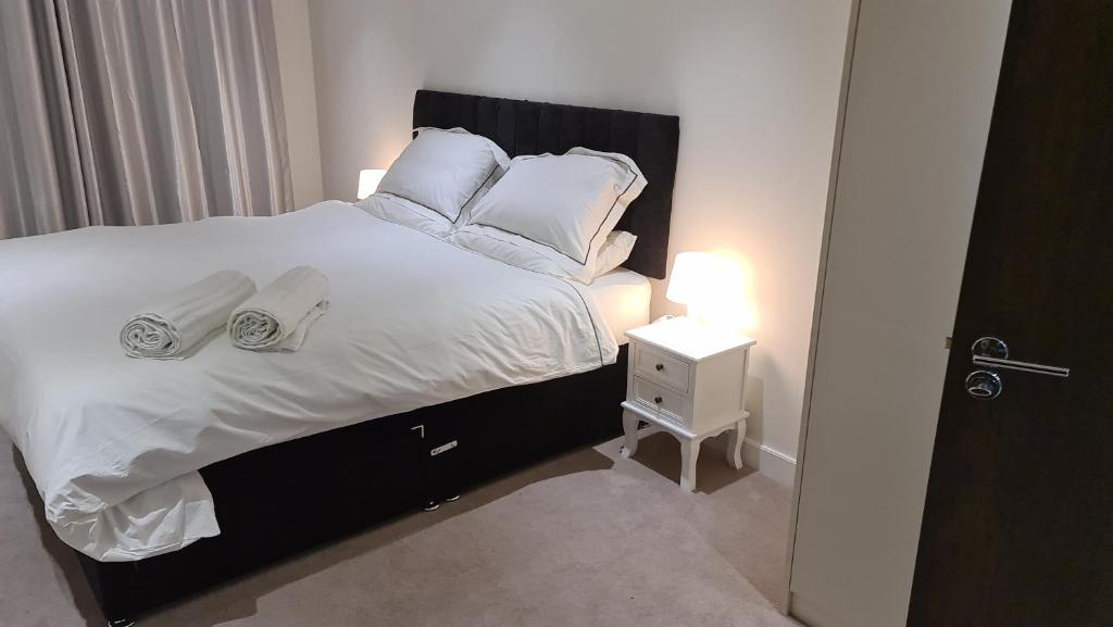 a bedroom with a bed with white sheets and pillows at Cushy Apartments, Colindale in Colindale