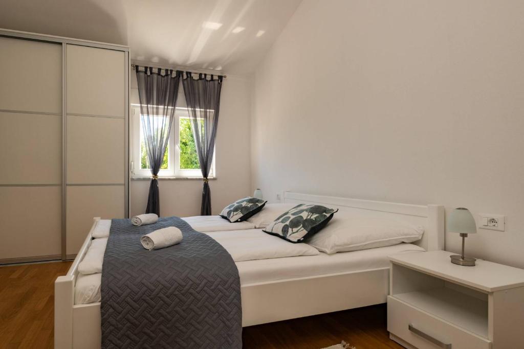 a white bedroom with a bed and a window at Villa Ellen Sophie in Vržnaveri
