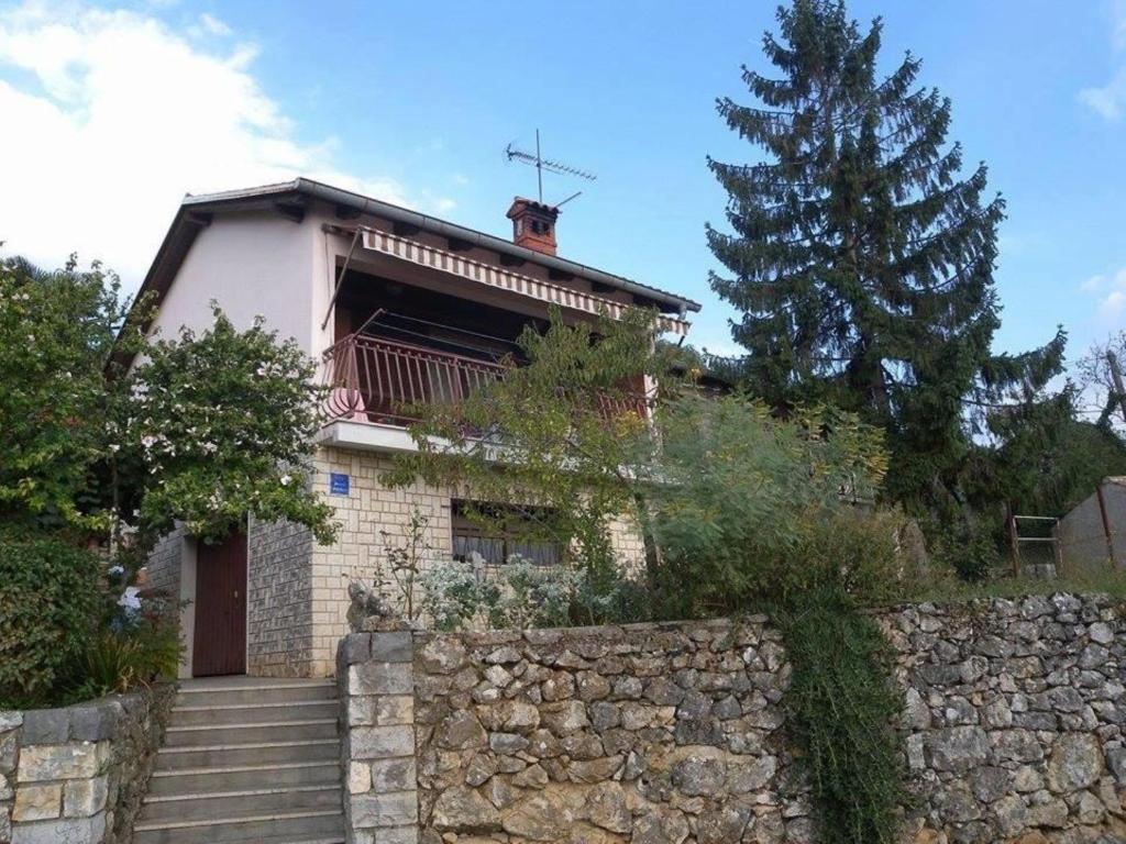 a house with a stone wall and a tree at Apartment Drazen in Mošćenice