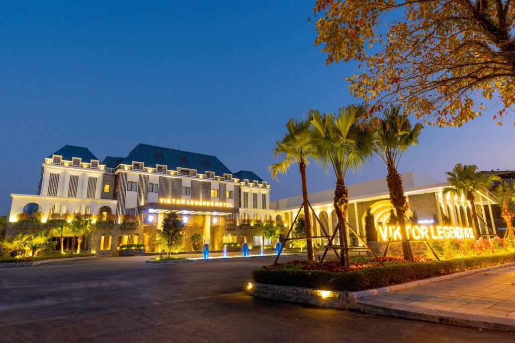 a building with palm trees in front of a street at Viktor Legends Hotel in Móng Cái