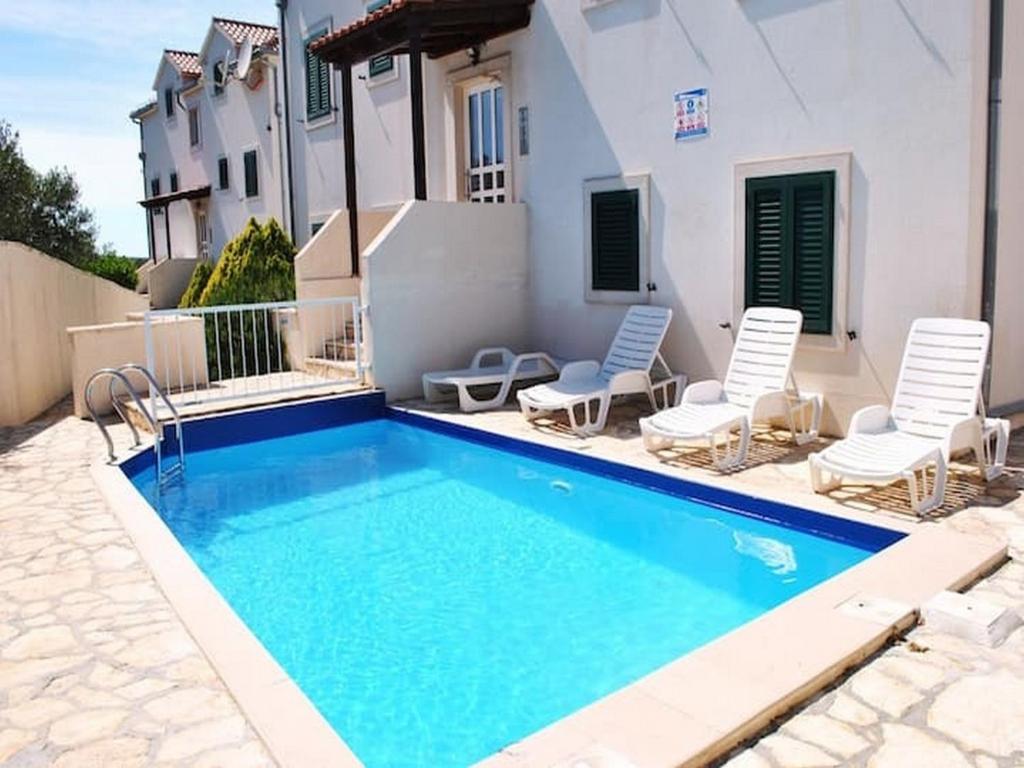 una piscina con due sedie e una casa di Apartment Sunflower a Supetar (San Pietro di Brazza)