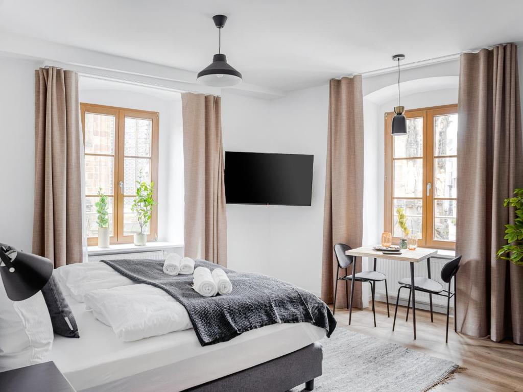a white bedroom with a bed and a table and chairs at limehome Zwickau Hauptmarkt in Zwickau