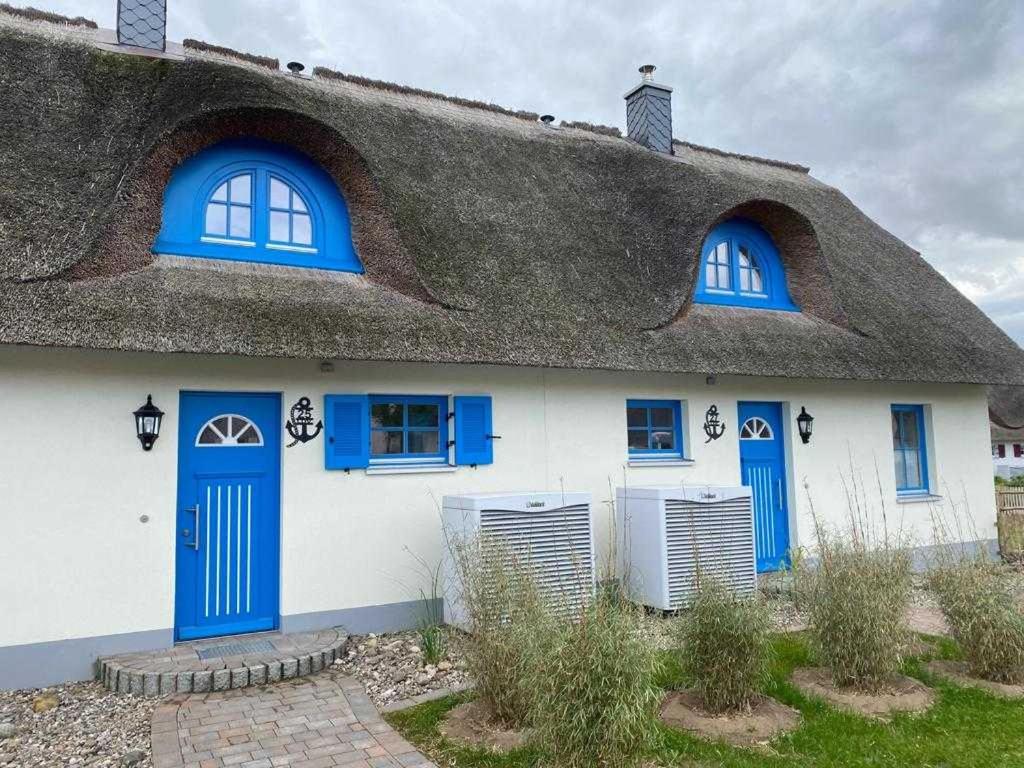 Cette maison blanche dispose de fenêtres bleues et d'un toit de chaume. dans l'établissement Ferienhäuser Luv und Lee OVS 106 Neu 20, à Zierow