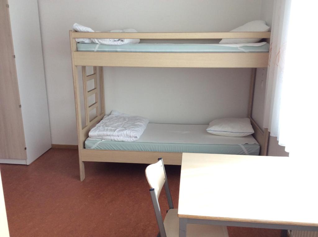 mały pokój z 2 łóżkami piętrowymi i stołem w obiekcie Atelier & Herberge ViDo w mieście Burg-Reuland