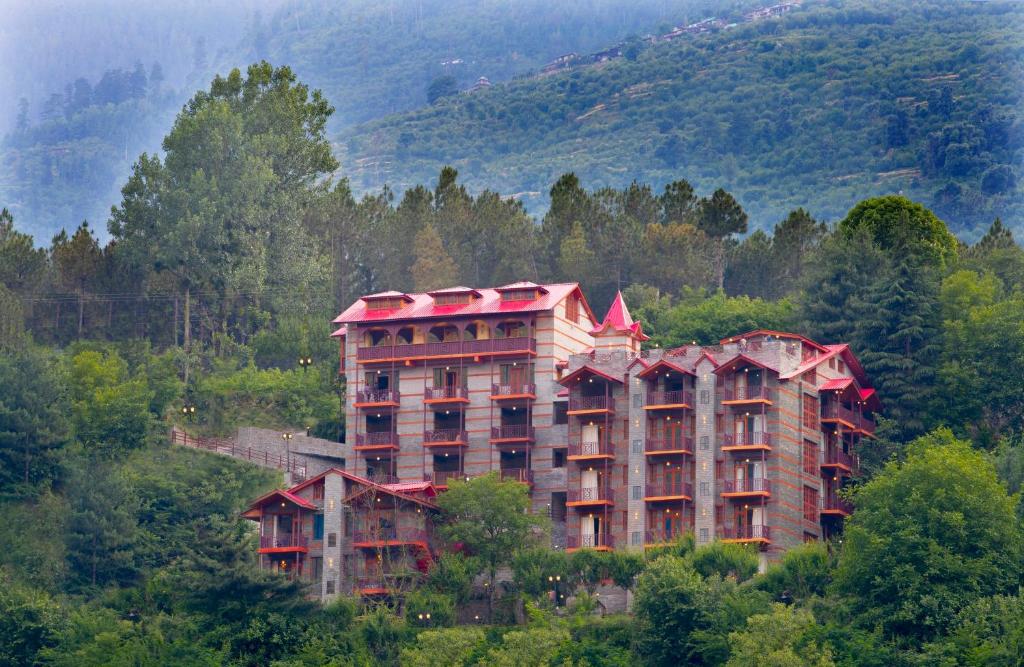 a large building in the middle of a mountain at Regenta Inn by Riverside Manali in Manāli