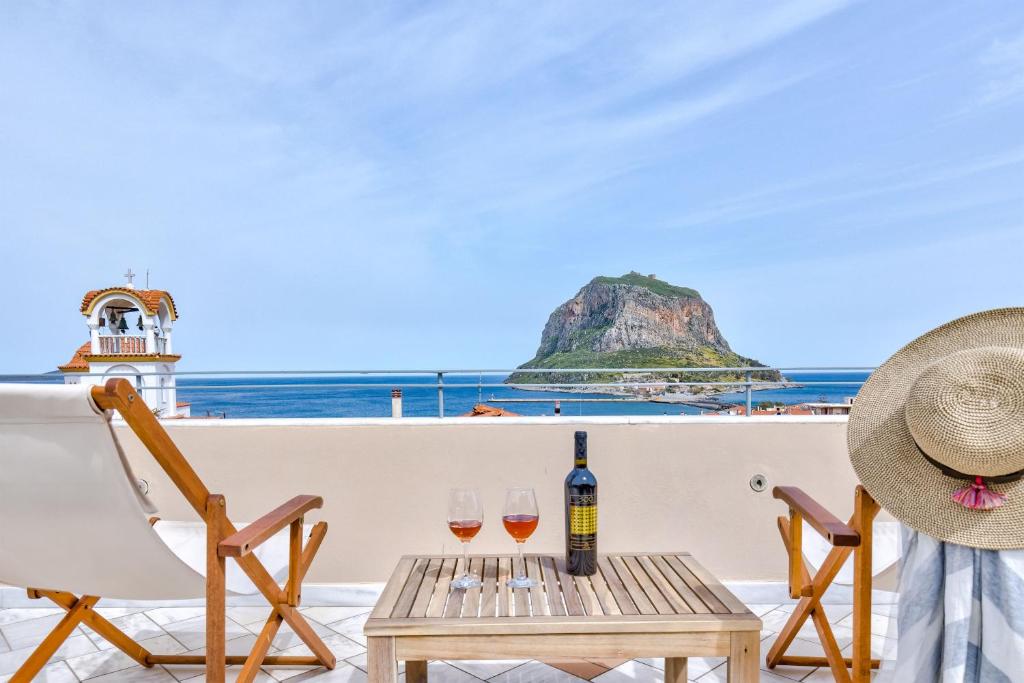a table and two glasses of wine on a balcony at Monemvasia Modern Flat with Panoramic Sea View in Monemvasia