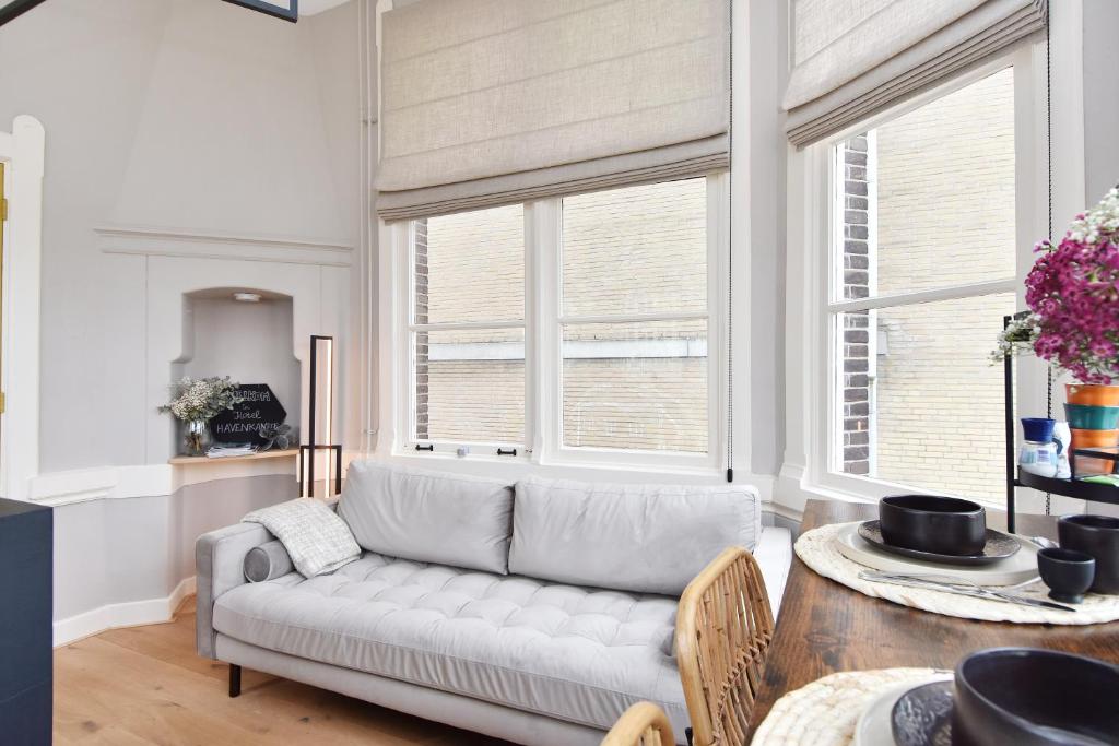 een woonkamer met een bank en 2 ramen bij Boutique Hotel Havenkantoor in Den Haag