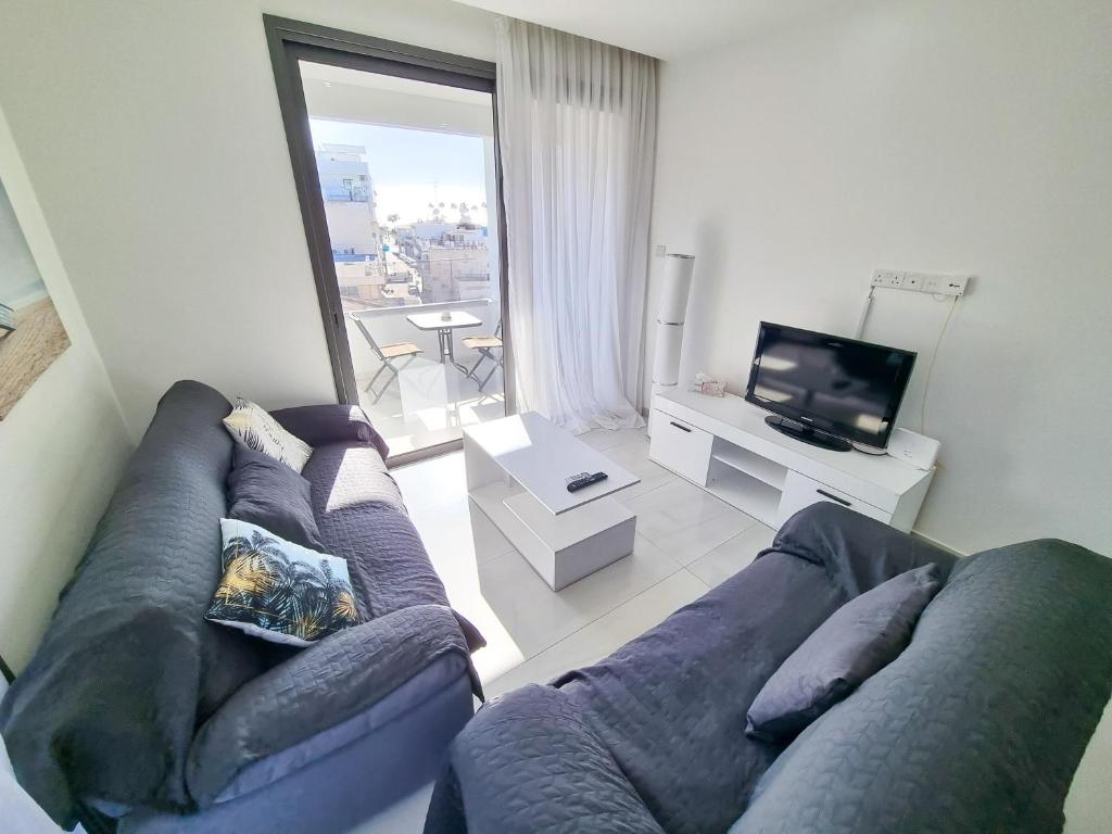 a living room with a blue couch and a tv at Sea La Vie Seaview Apartment in Larnaka