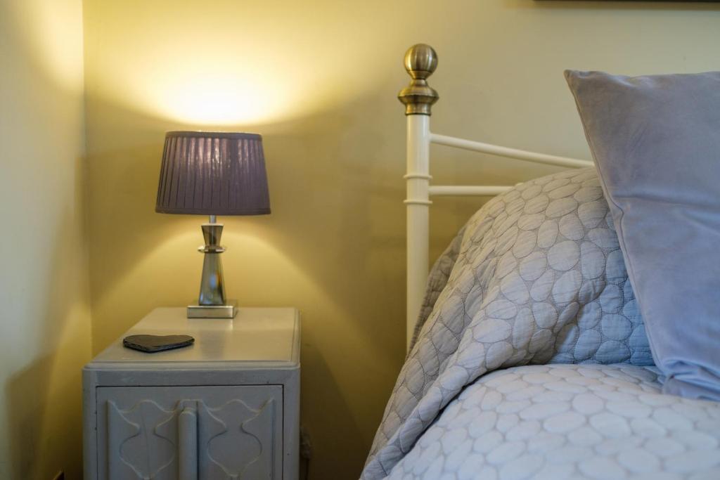 a bed with a nightstand with a lamp on it at Just a Minim - quaint studio in beautiful rural retreat in Rushford