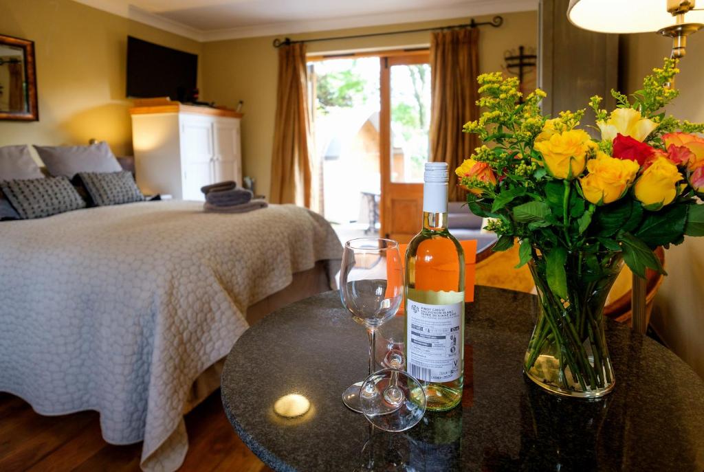 a room with a bottle of wine and flowers on a table at Just a Minim - beautiful studio & hot tub available ! in Rushford