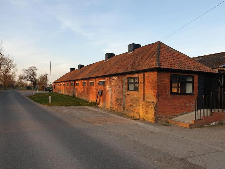 een oud bakstenen gebouw aan de kant van een straat bij The Old Dairy Accommodation in Tillingham
