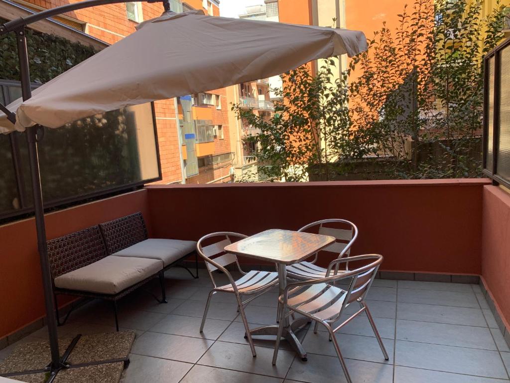 una mesa con sillas y una sombrilla en el balcón en Scendi dal treno, en Bolonia
