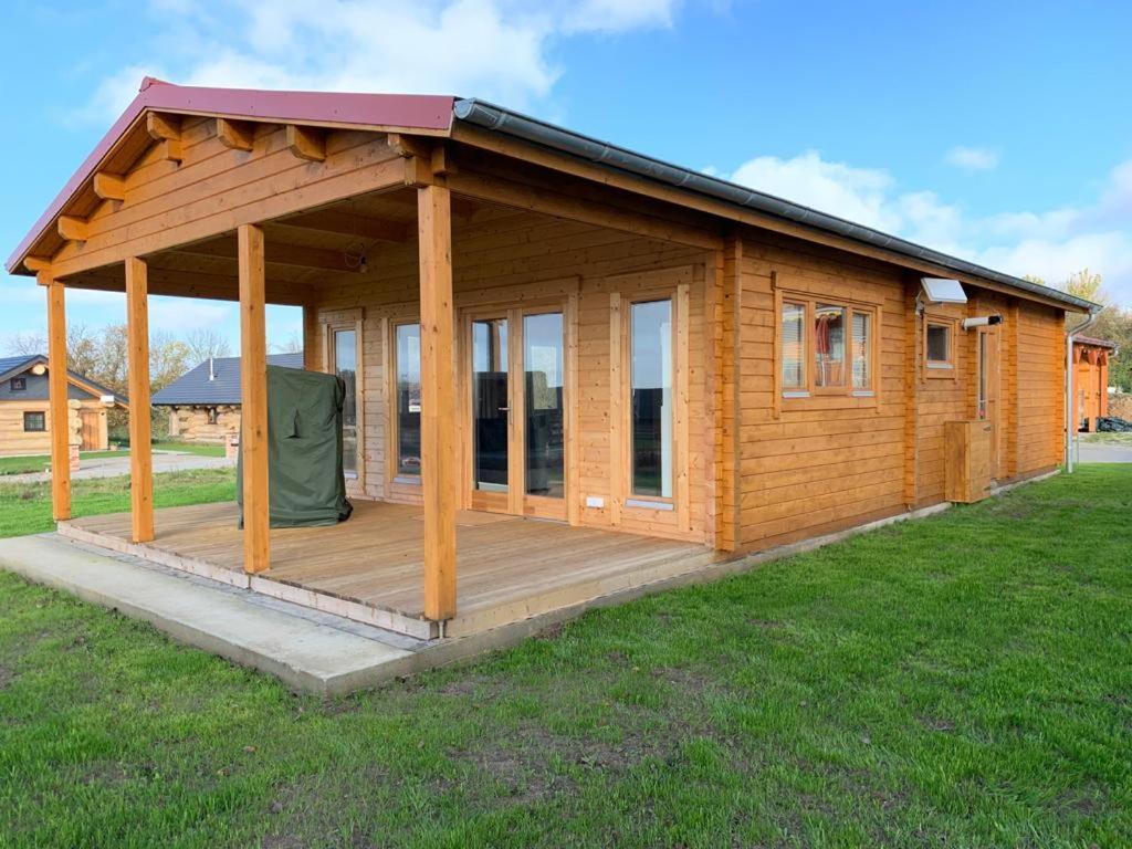 a wooden cabin with a deck in the grass at Ferienhaus Tollensesee in Groß Nemerow