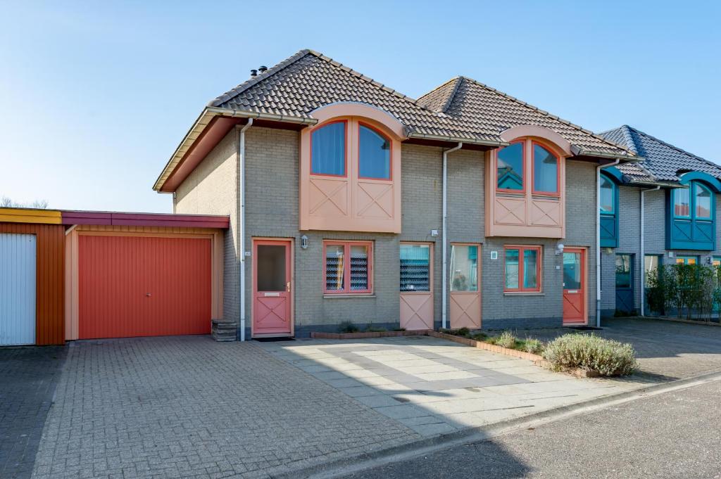 een huis met oranje deuren en een rode garage bij Grasse 142 - Kustpark Village Scaldia in Hoofdplaat