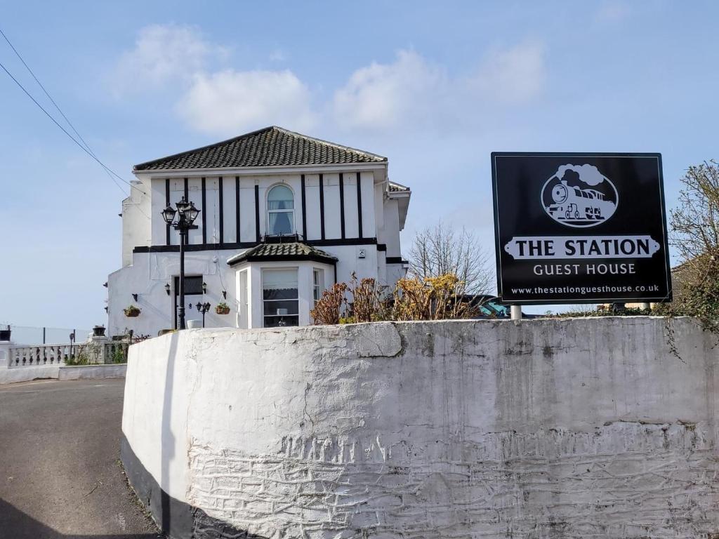 um sinal para a casa de hóspedes da estação em frente a um edifício em The Station Guest House em Brixham