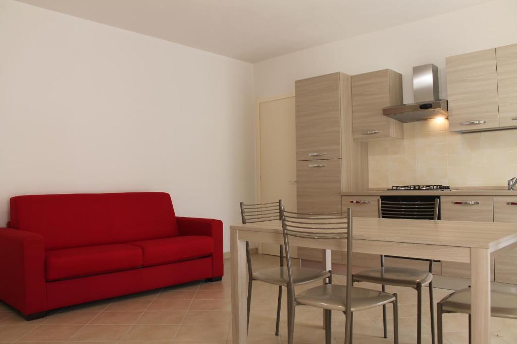 - un salon avec un canapé rouge, une table et des chaises dans l'établissement Luisa bilocale con giardino, à Castagneto Carducci