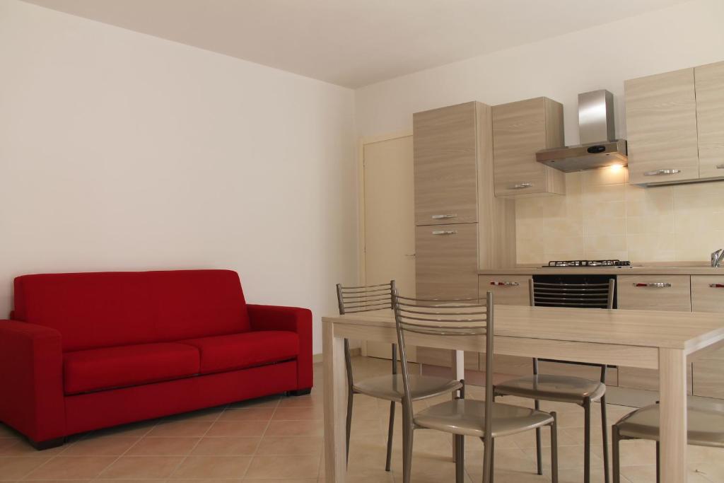 a living room with a red couch and a table and chairs at Luisa bilocale con giardino in Castagneto Carducci