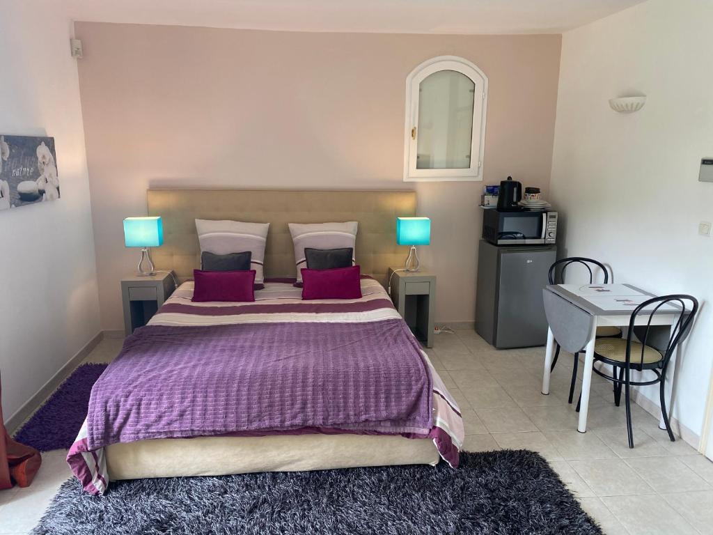 um quarto com uma cama roxa, uma mesa e cadeiras em Chambre spacieuse indépendante dans villa plus parking privée em Le Cannet