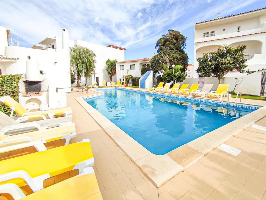 a swimming pool with yellow chairs and a hotel at Apartamentos Pedro for Families by Bedzy in Albufeira