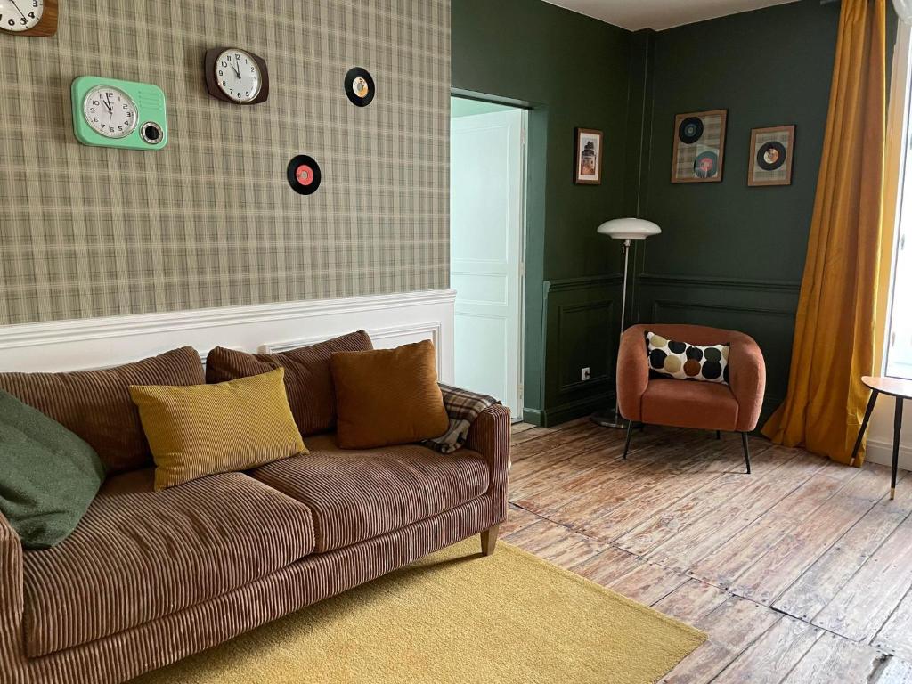 a living room with a brown couch and a chair at NAMASTE COTTAGE in Issigeac
