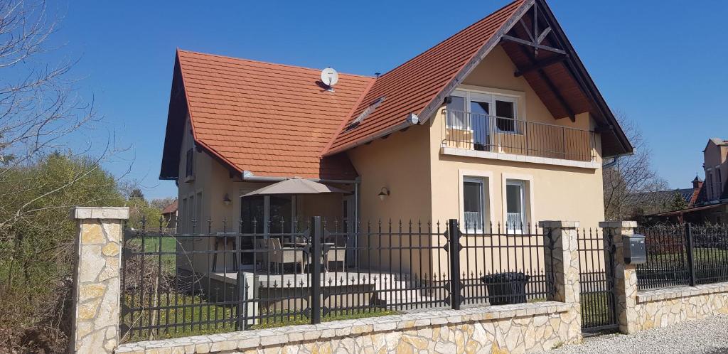 ein Haus mit einem Eisenzaun davor in der Unterkunft Balaton Villa in Gyenesdiás