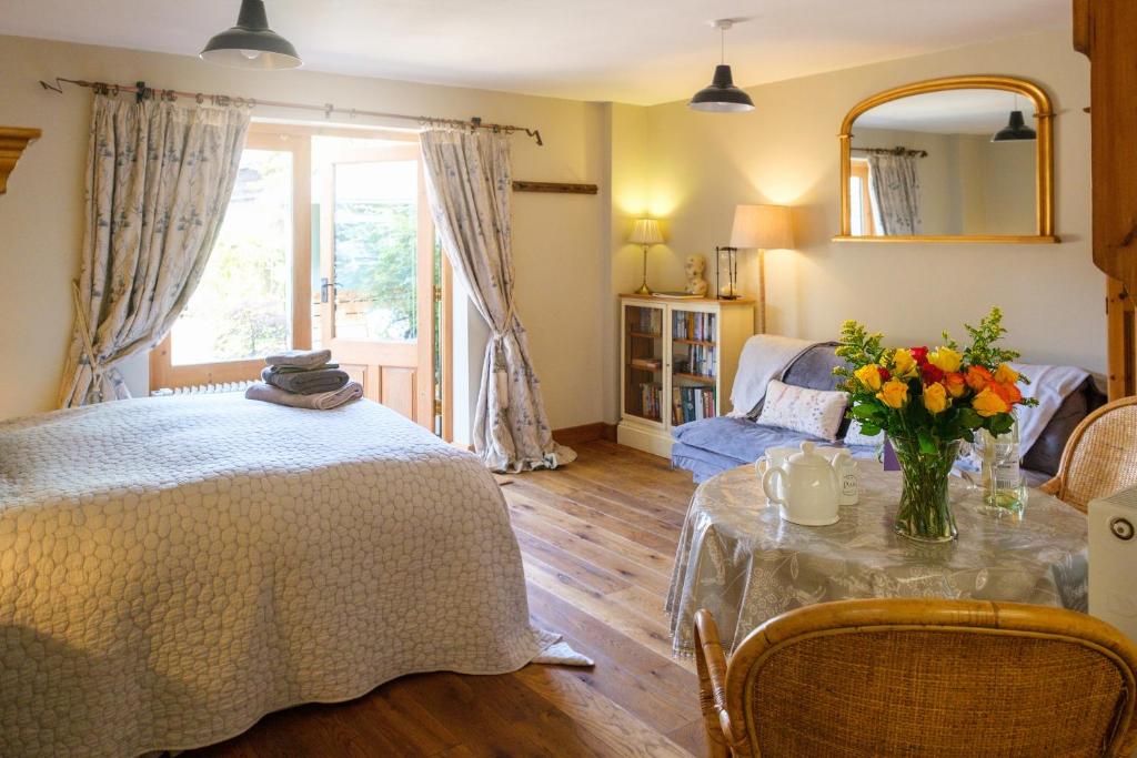 a living room with a table with flowers on it at Quavers Rest - a quintessential little home & hot tub available ! in Rushford