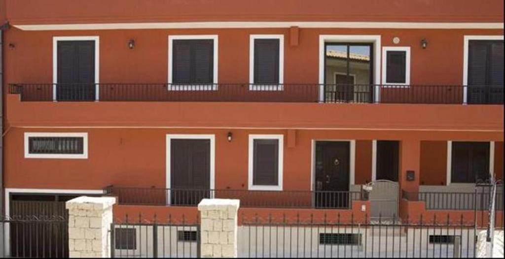 ポッツァッロにあるB&B Alloggi Buonaseraの黒いドアとバルコニー付きのオレンジ色の建物