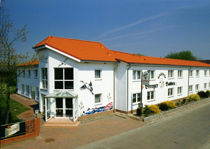 ein großes weißes Gebäude mit orangefarbenem Dach in der Unterkunft Gasthof Breeger-Bodden in Breege