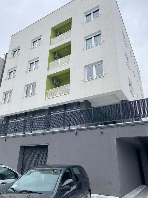 a white building with cars parked in front of it at New Apartment in the City in Visoko
