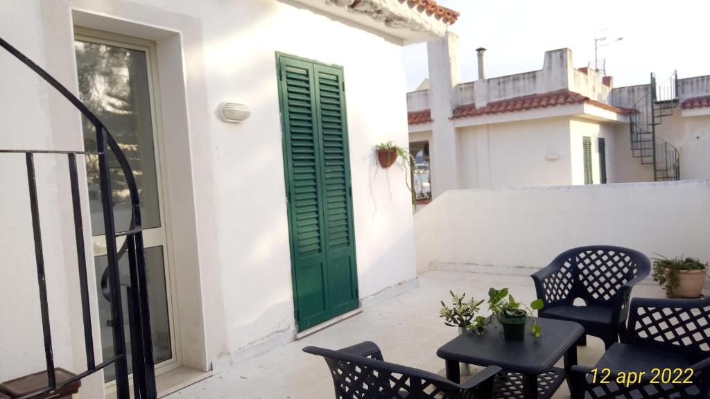 a green door on a white house with chairs and a table at Holiday Home Sulmare in Isola delle Femmine