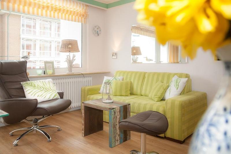 ein Wohnzimmer mit einem gelben Sofa und einem Tisch in der Unterkunft Duen12_ 9 in Westerland