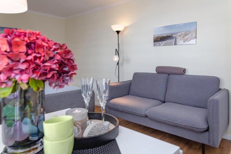 uma sala de estar com um sofá e uma mesa com flores em Strandkoenig 4 _AD1 _ 206_ em Westerland