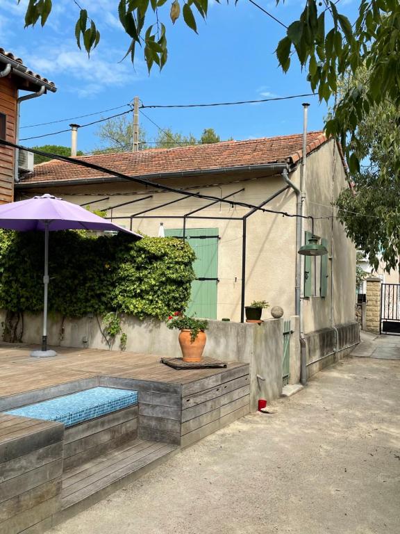 a house with a swimming pool and an umbrella at MAZET avec spa in Nîmes