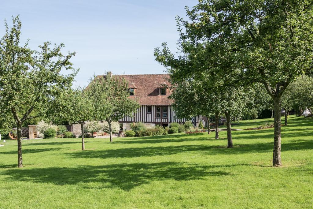 una casa grande con árboles delante de ella en Locations - Domaine Le Coq Enchanté en Cambremer