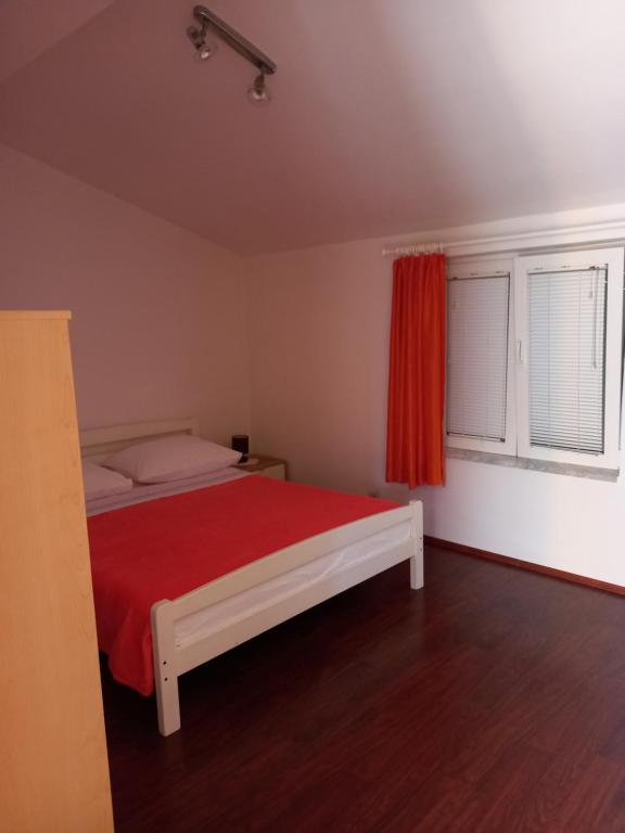Apartments Mirjana في بيتريتشاني: غرفة نوم بسرير وبطانية حمراء