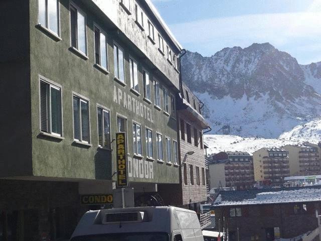 ein Gebäude mit einem schneebedeckten Berg im Hintergrund in der Unterkunft Aparthotel Condor in Pas de la Casa