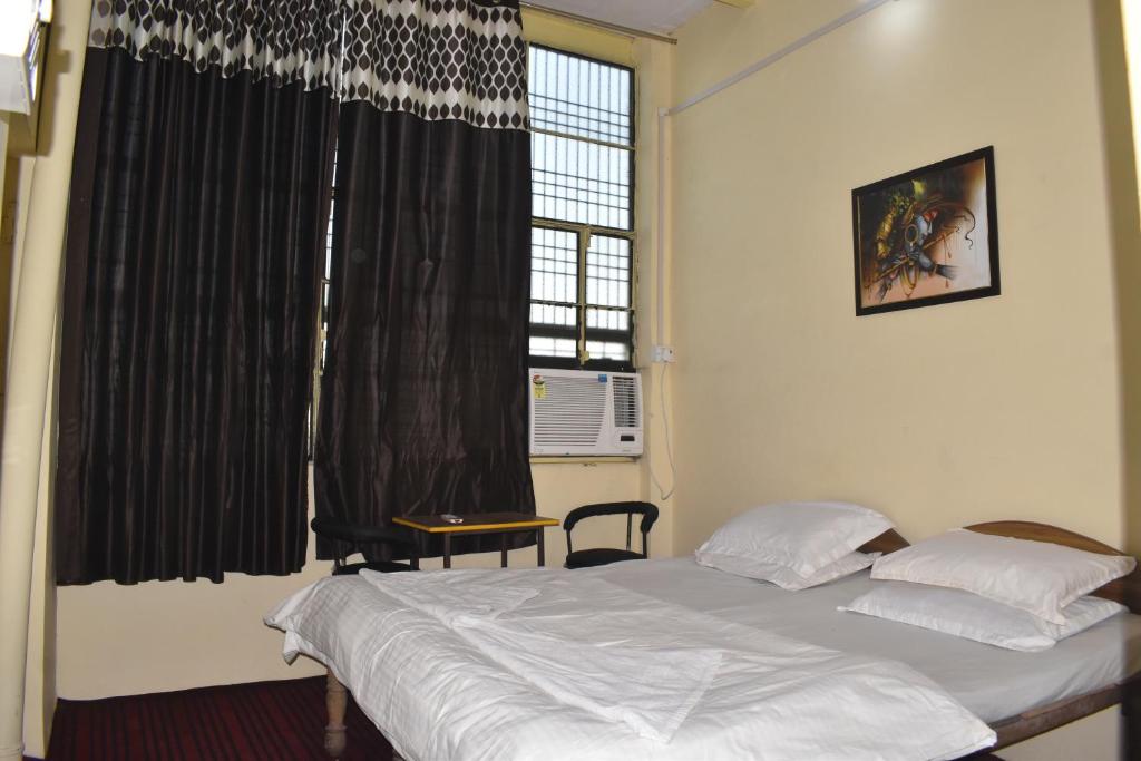 a bedroom with a bed and a large window at OM REST HOUSE in Varanasi