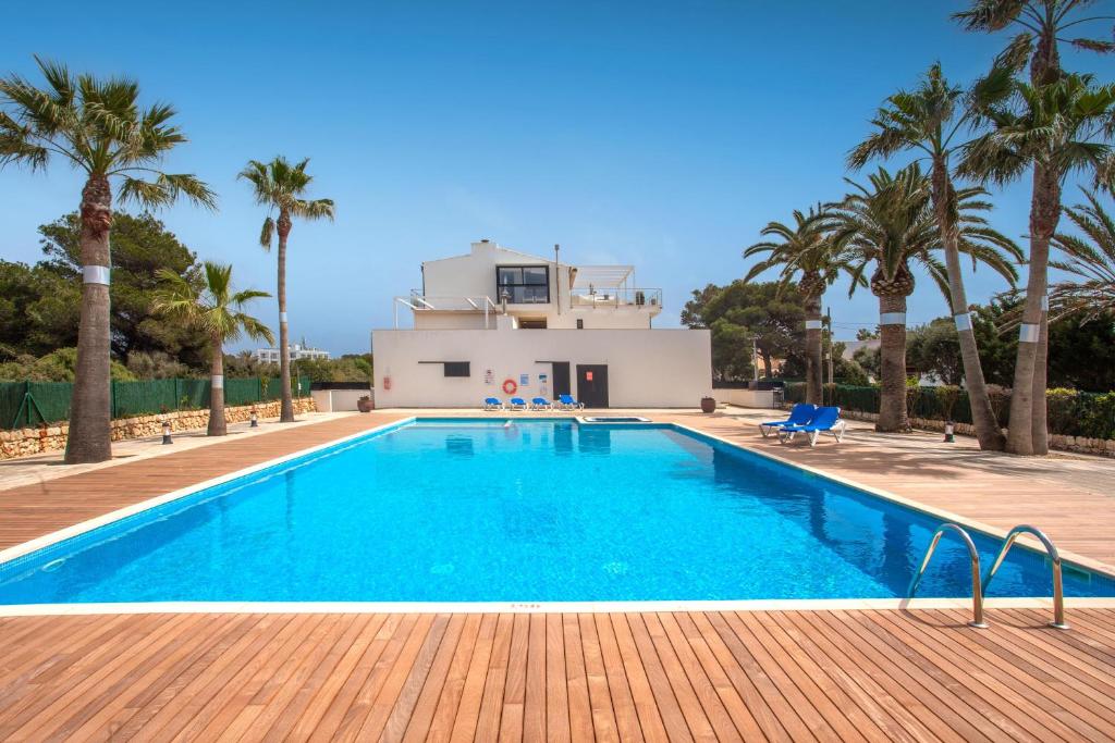 uma piscina com palmeiras e uma casa em Menorca Blue em Cala Santandria