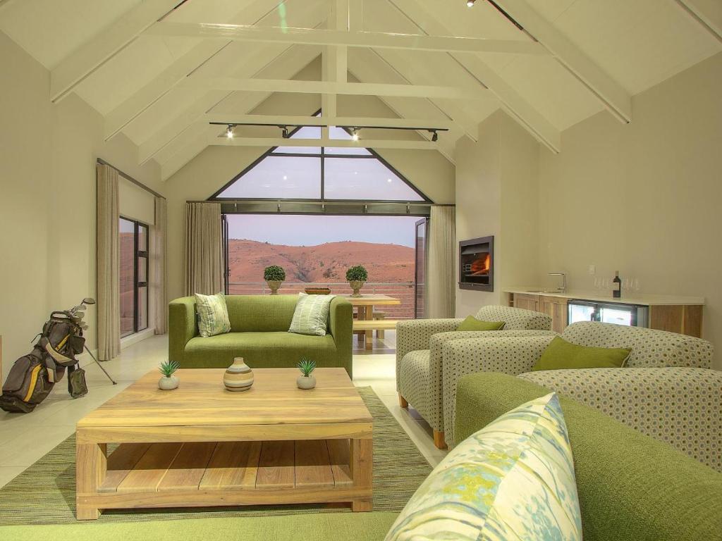 a living room with green furniture and a table at Highland Gate Ferox Creek in Dullstroom