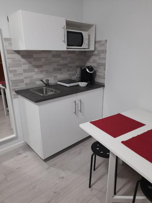 a kitchen with white cabinets and a sink and a table at Your Independent Room with parking in Lecco