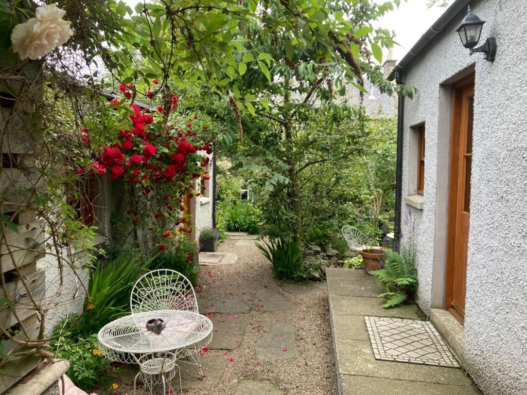 un petit jardin avec une table, des chaises et des roses dans l'établissement Entire unique tiny house - Moss Cabin, à Banff