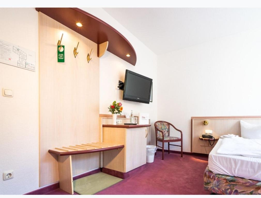 a hotel room with a bed and a desk and a tv at Hotel Tanne in Saalfeld