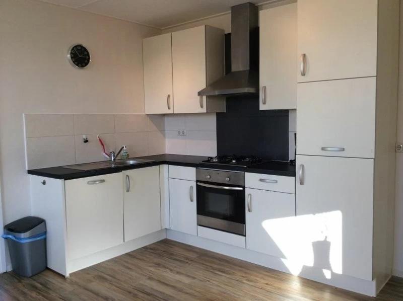 een keuken met witte kasten, een wastafel en een fornuis bij Appartement Zilt in Hollum