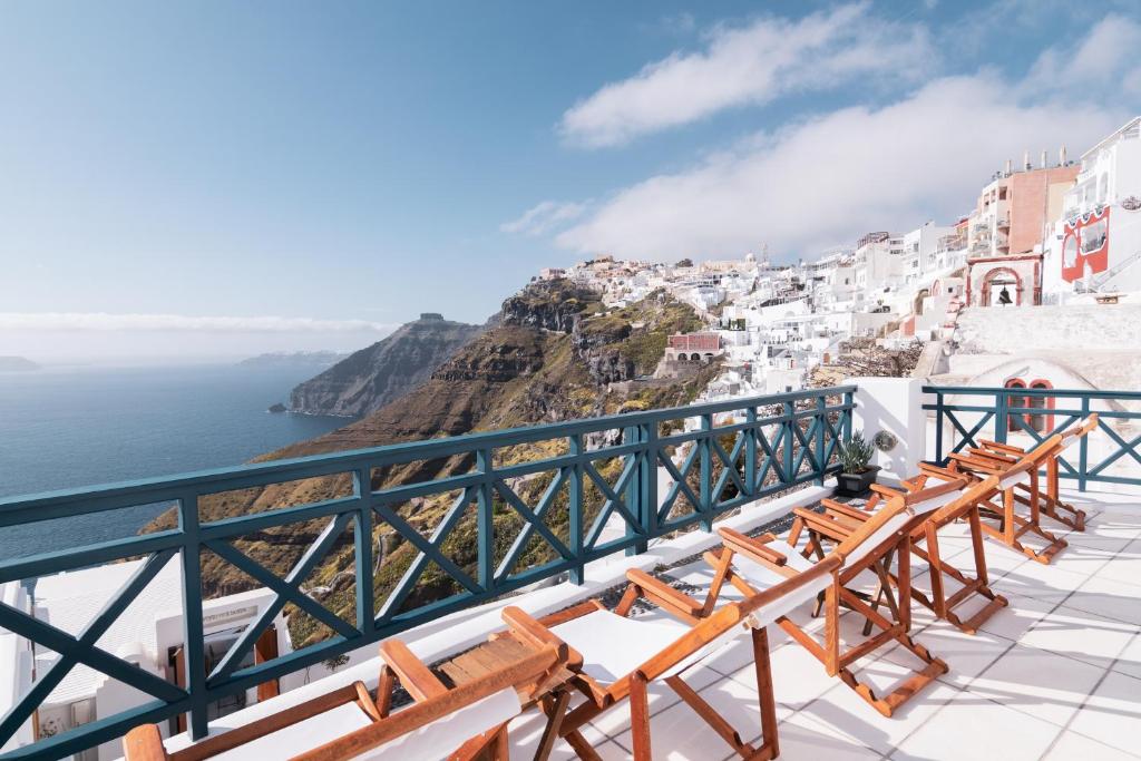 a view of the amalfi coast from a balcony with wooden benches at DELION VIEW HOTEL in Fira